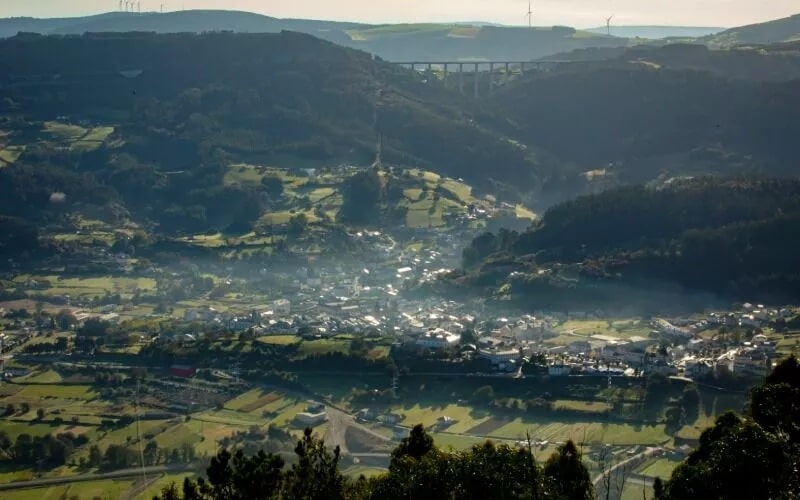 Top view of a green valley, with houses and a few roads