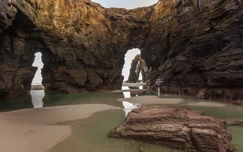 A spot on the beach surrounded by rocks resembling archways