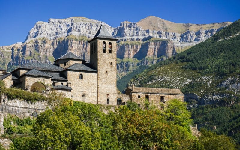 A beautiful church with a tower in front of the mountains