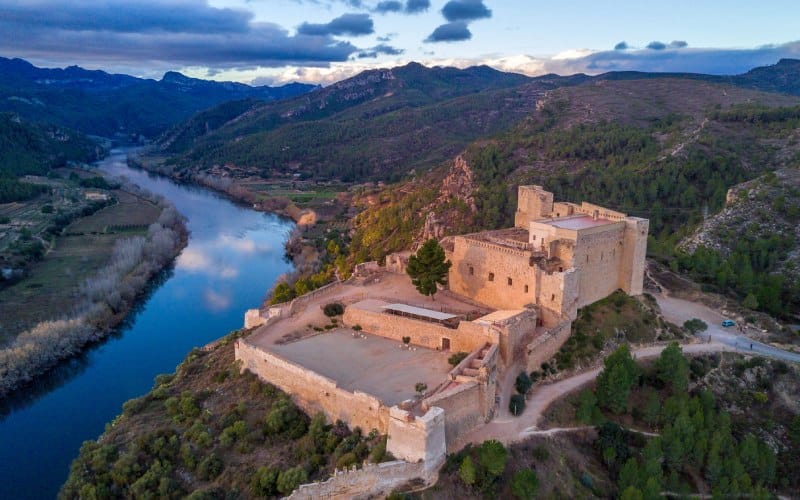 A panoramic view of a castle over a cliff and a river