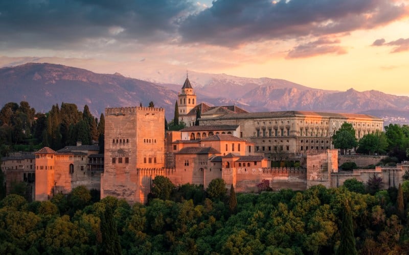 Some ancient buildings at sunset and mountains in the background