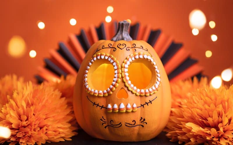 A pumpkin decorated with Mexican motifs with an orange background and flowers