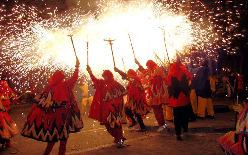 People dressed with bright colours, dancing and carrying torches