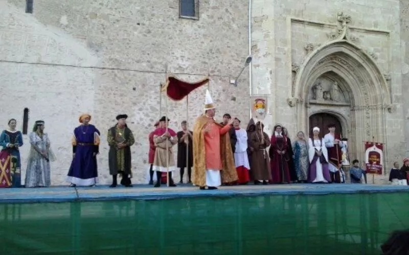 Some people in a stage in front of a cathedral, dressed in medieval clothing