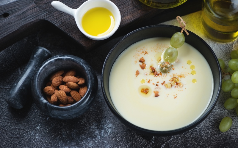 A white soups with grapes and almonds on the side