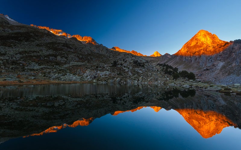 A mountain range over a lake, one of the highest peaks in Spain