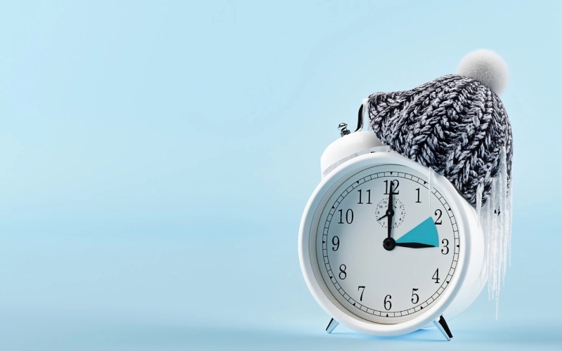A white clock with a wool cap and a plae blue bakcground