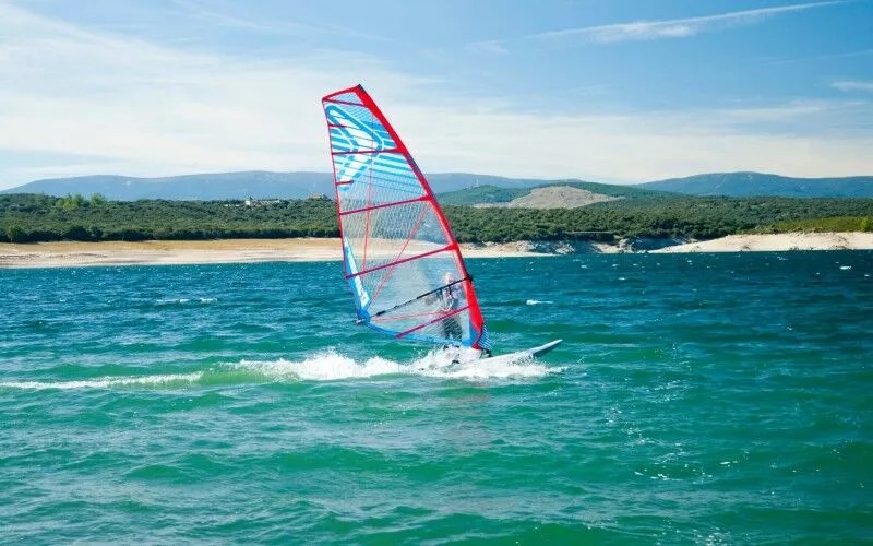 A person windsurfing in the blue waters of the reservoir of Atazar