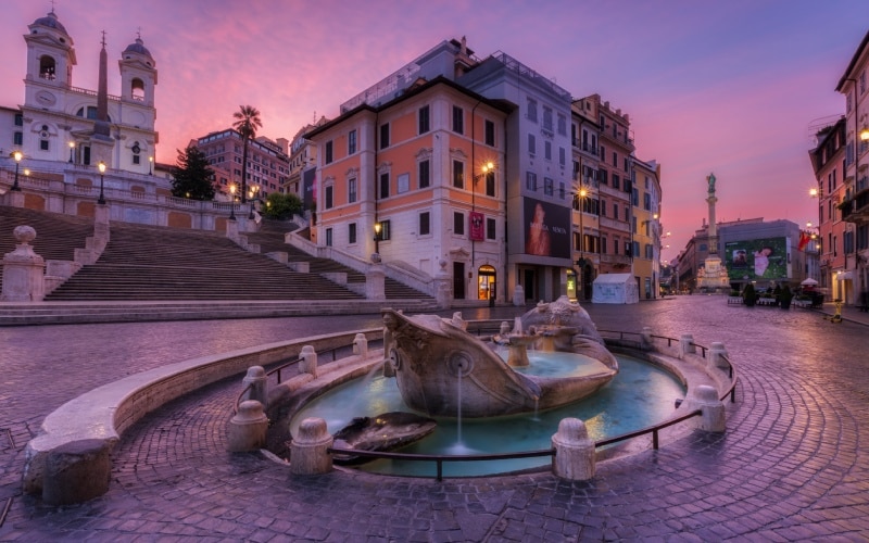 The Spanish square and its fountain at sunset with a purplish light