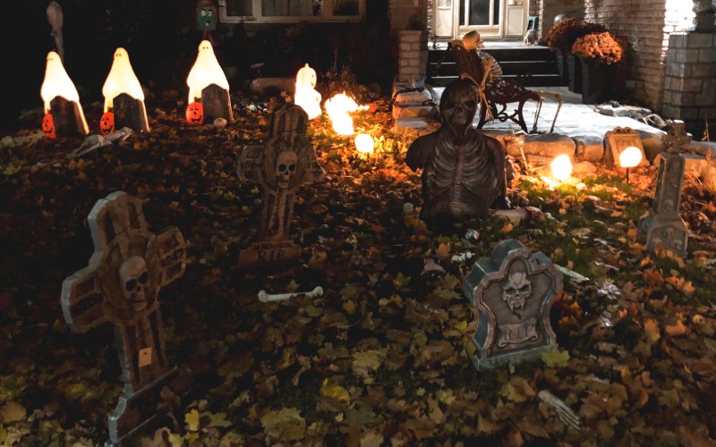 Frontyard of a house with Halloween decorations, like skeletons, graves and pumpkins