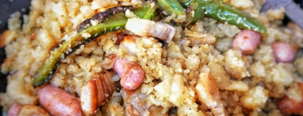 A dish of yellowish crumbs with meat and green peppers