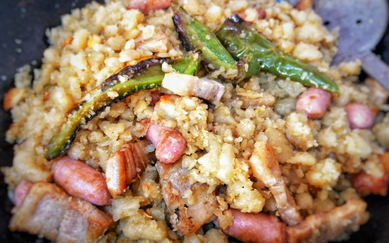 A dish with yellow crumbs, meat and green peppers