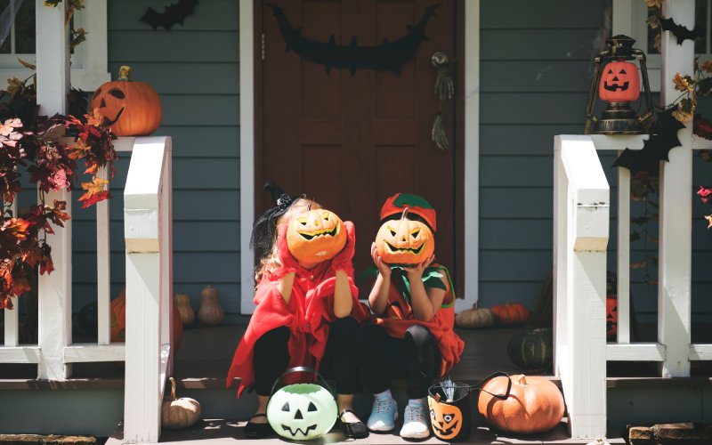 Children in Halloween costumes on a porch with pumpkins