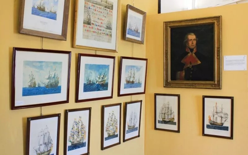 A series of nautical paintings on a yellow wall