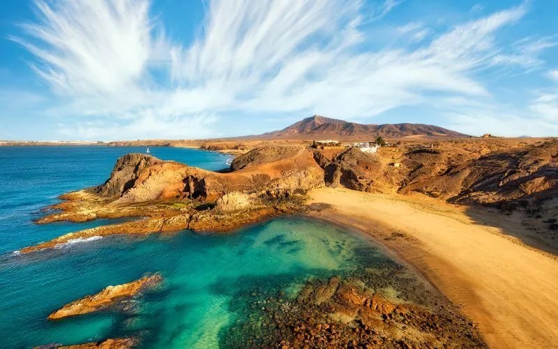 A panoramic view of a beach in red volcanic land