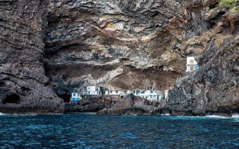 A series of white houses on a rock cliff right next to the sea