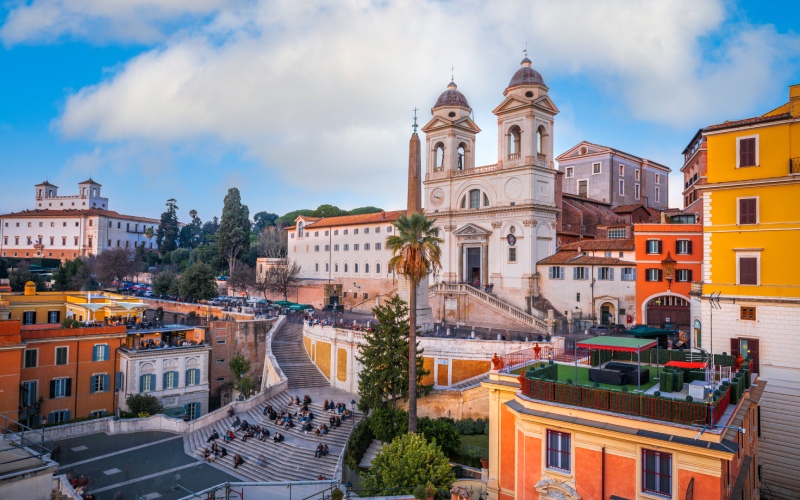 The Spanish square in Rome with a church, a staircase and colourful buildings 