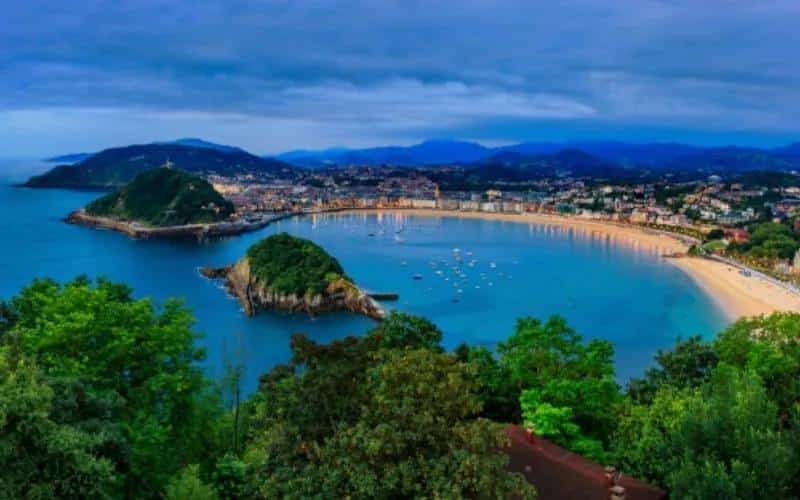 A panoramic view of the Bay of Donostia, with an island and two beaches