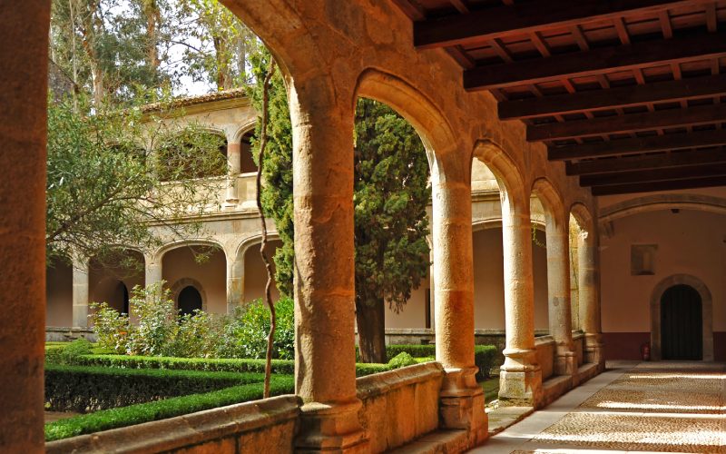 A cloister witch archways on the side, leading to a patio with trees