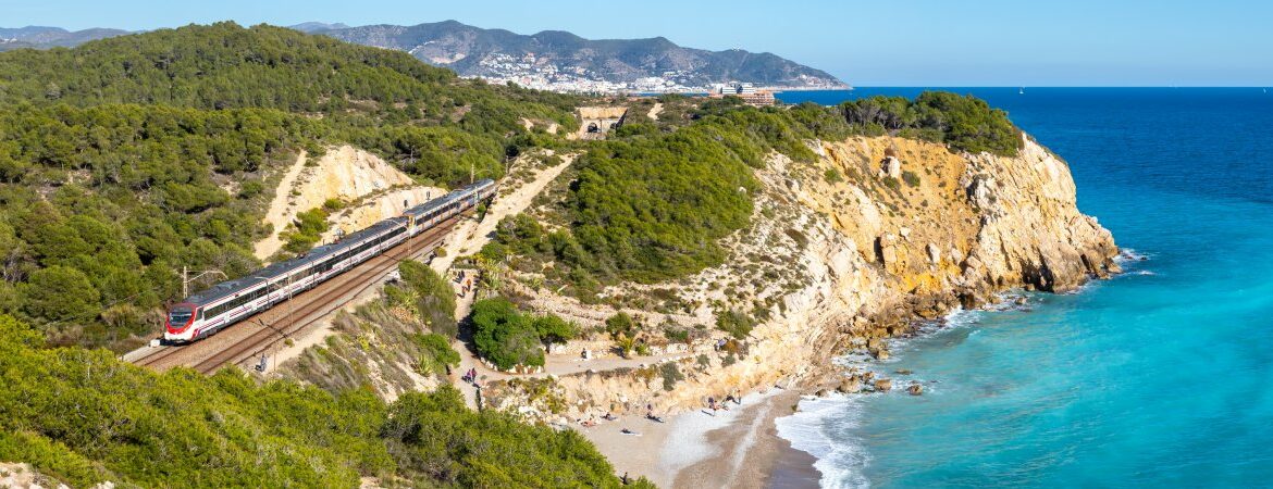 A train on a railroad next to the sea