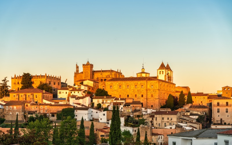 Panoramic view of the city of Cáceres with a church and other buildings at sunset